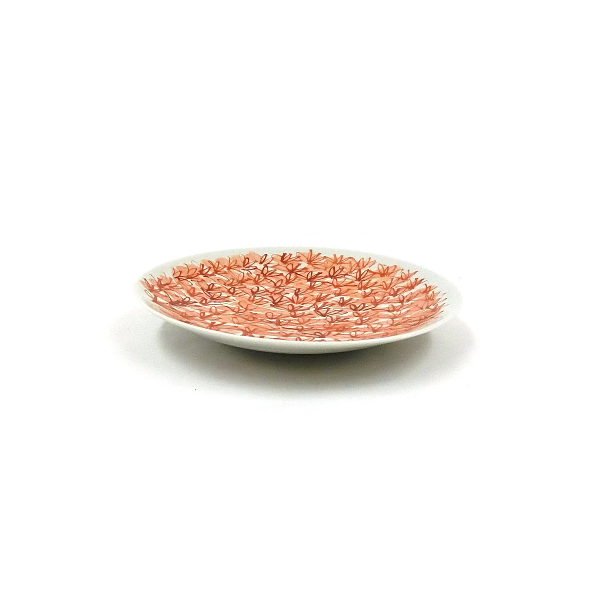 Side view of the plate showing its shallow profile and the red flowers running up to the rim.