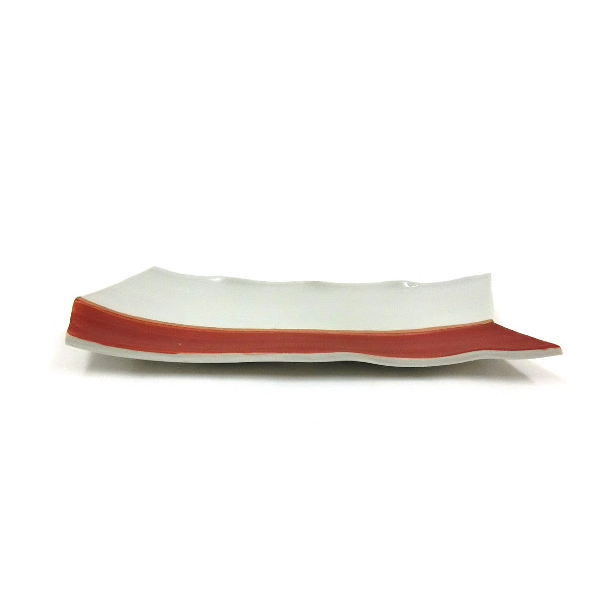 The plate seen end-on at a low angle, showing the shallow trough and the red painted rim.