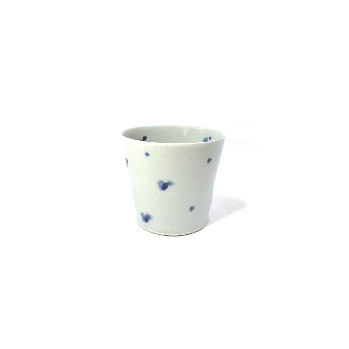Front view of the white porcelain cup on a white ground with small scattered blue flowers, slightly tapered toward the base.