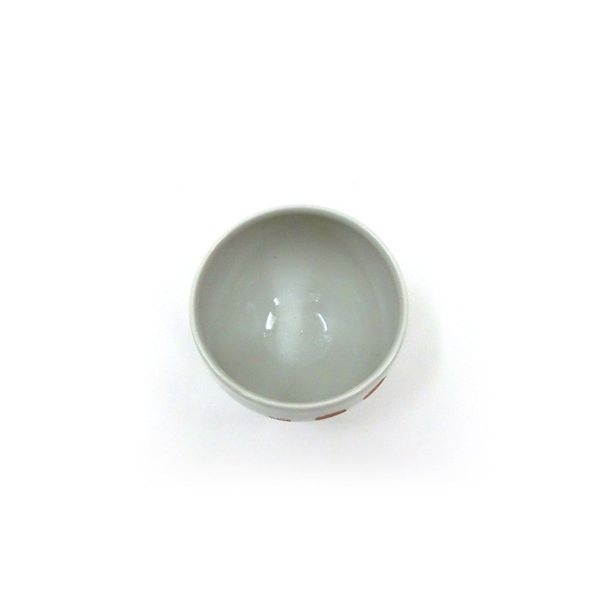 The cup tilted to show the interior and the smooth white glaze.