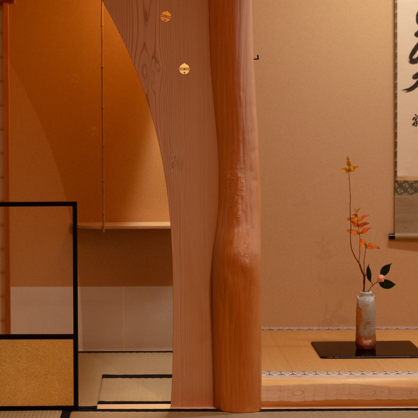 Naturally curved alcove post with inlaid circular motifs beside a hanging scroll