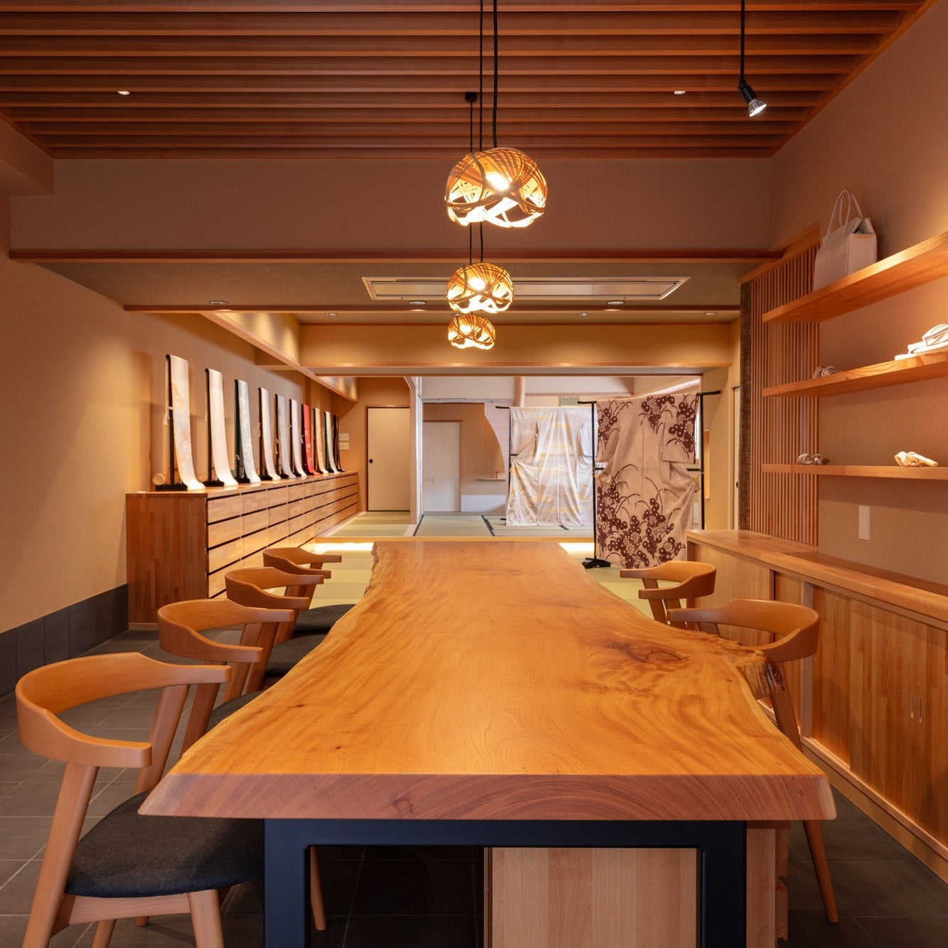 Live-edge timber counter with woven bamboo pendant lights, a warm Japanese interior