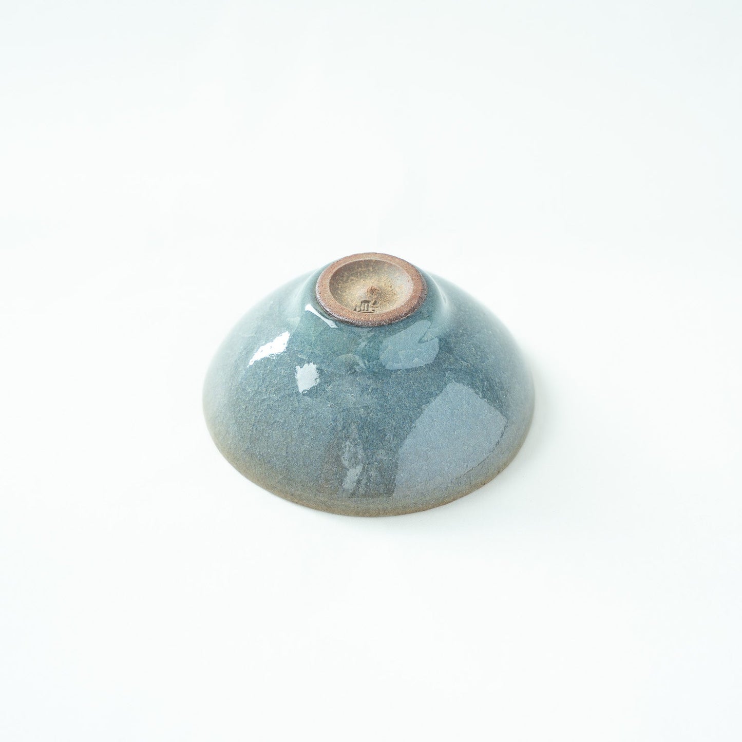 Inverted view of the SAKAZUKI, showcasing the unglazed dark clay base and the artist's stamped signature mark.