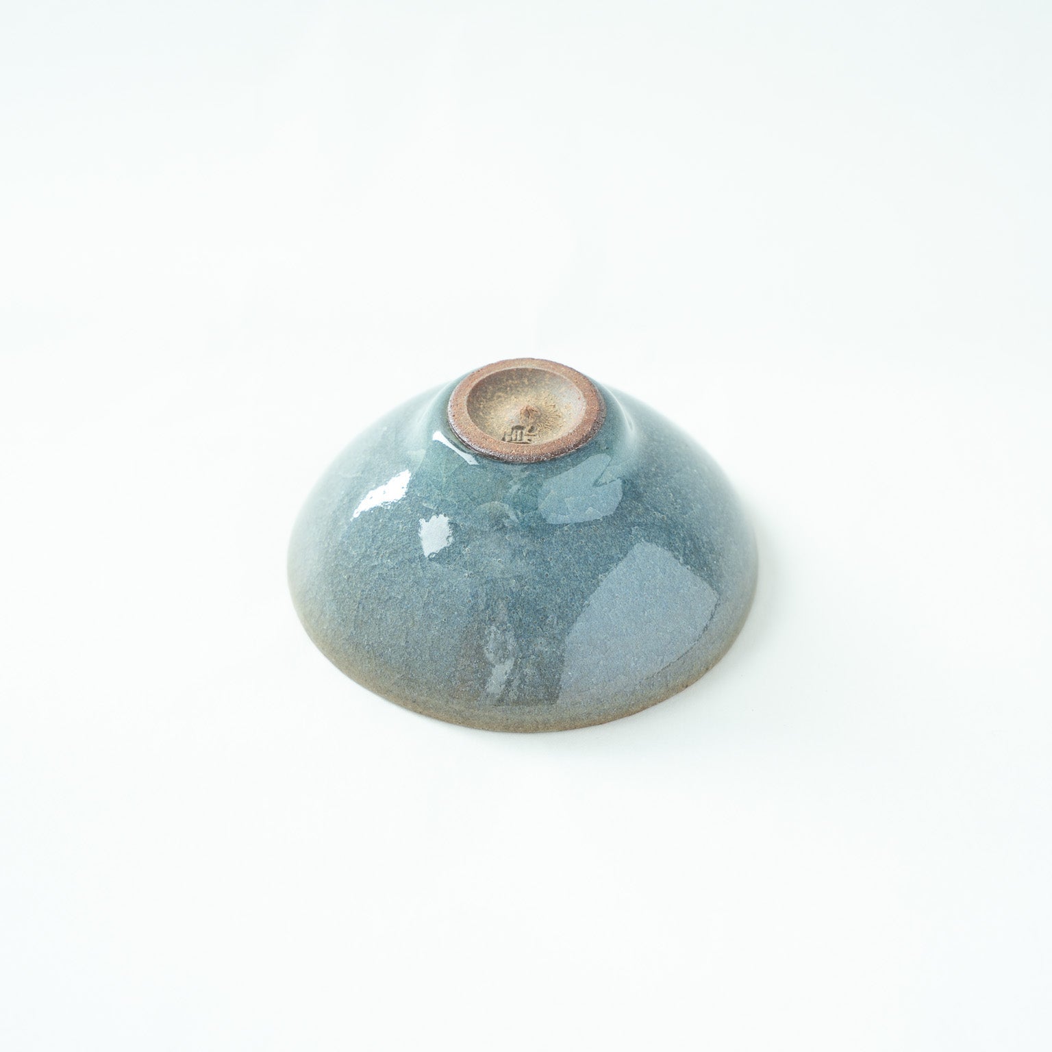 Inverted view of the SAKAZUKI, showcasing the unglazed dark clay base and the artist's stamped signature mark.