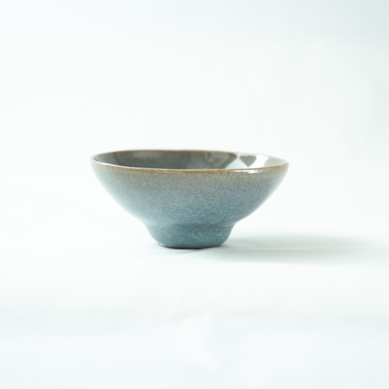 Clean profile shot of the Jun-style sake cup, capturing the slightly brownish, rustic rim texture against the smooth glazed body.