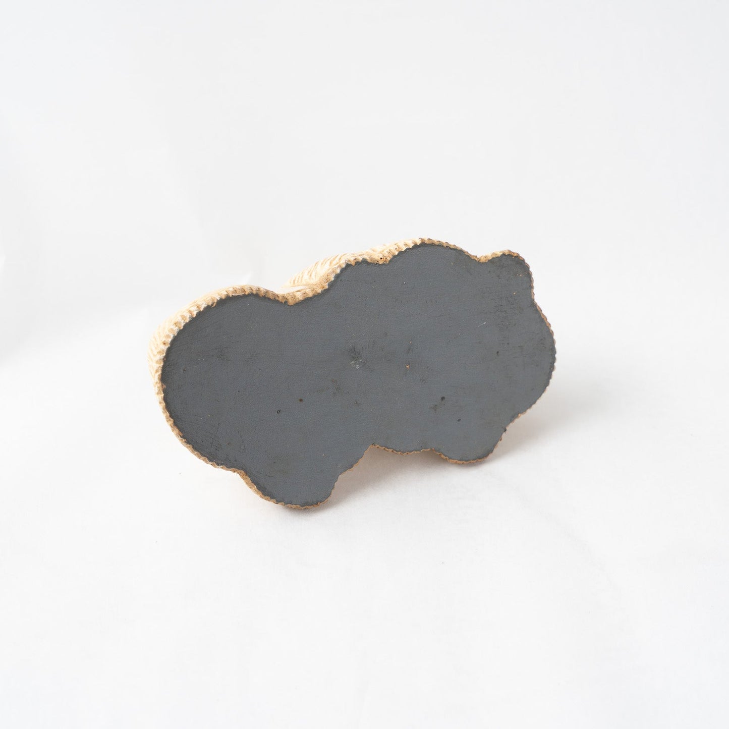 View of the flat, dark grey finished underside of the leather poodle paperweight, illustrating the seamless edge alignment of the molded leather technique.