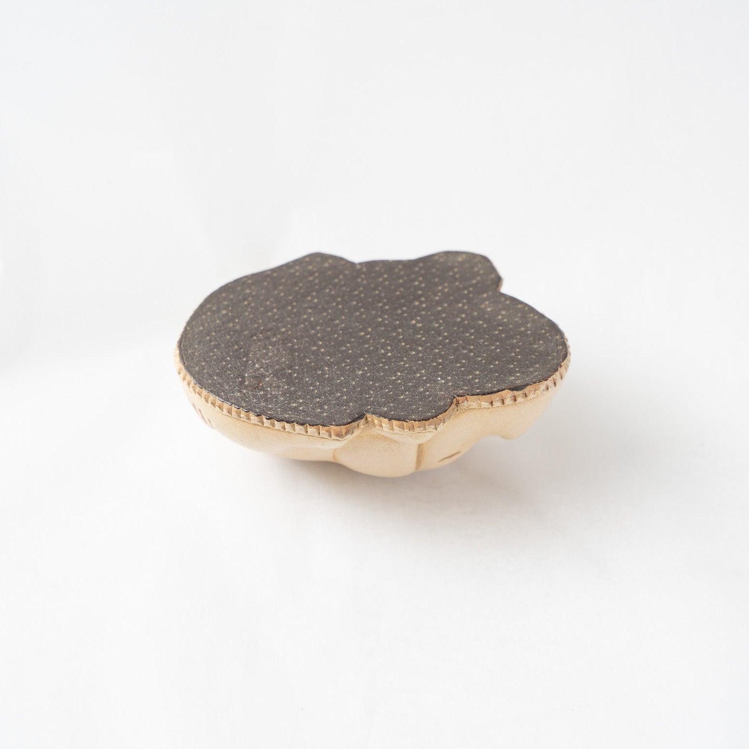 The textured, non-slip dark brown underside of the leather pig paperweight, showcasing the precise perimeter stitching and flat base.