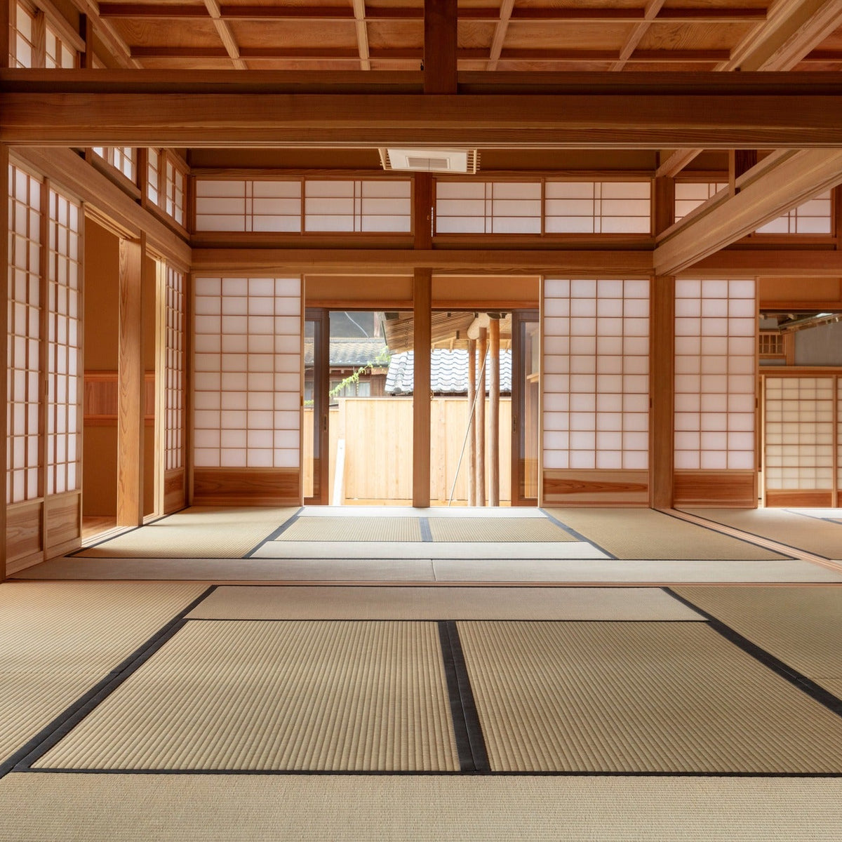 Linked tatami rooms opened into a single hall, framed by shoji and a high timber ceiling