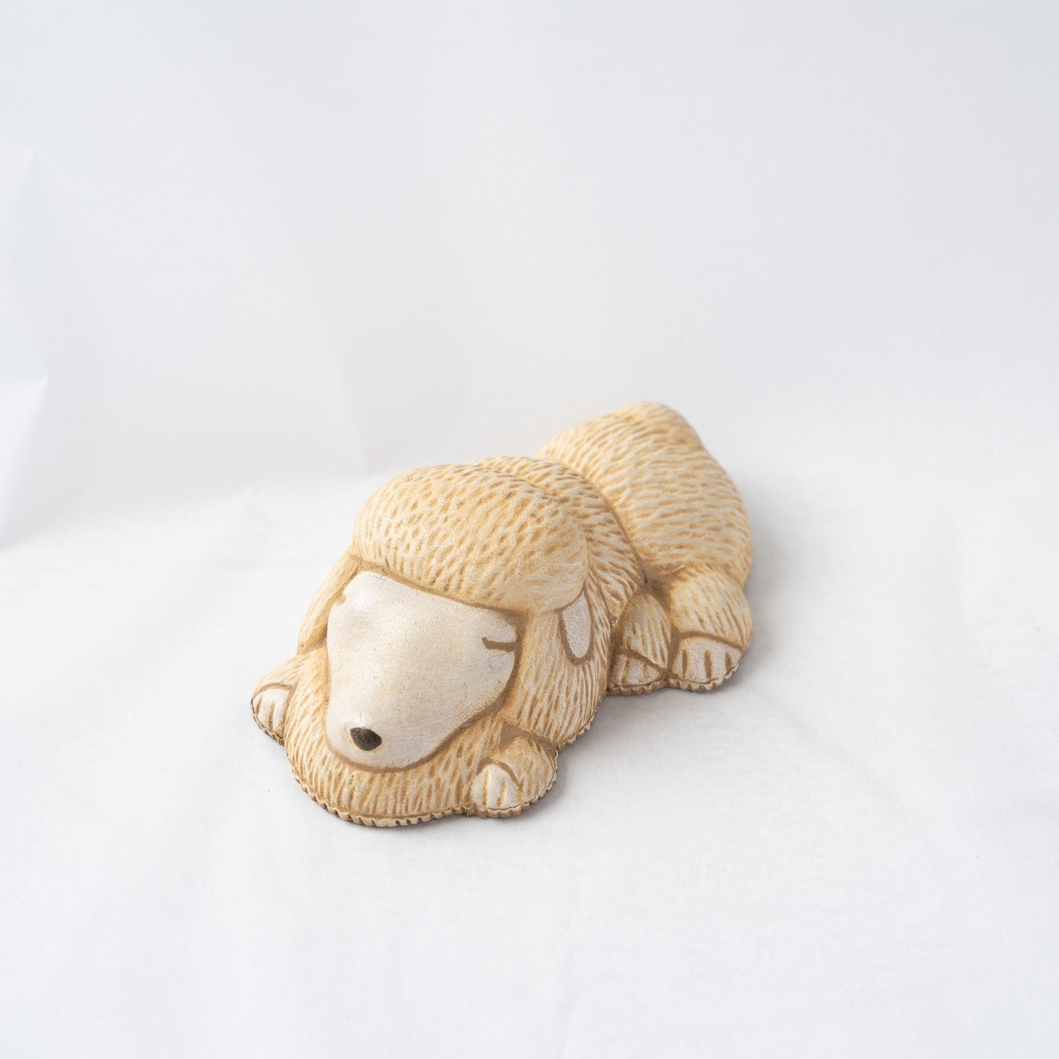 Front angled view of the leather poodle paperweight by Koh Kono, focusing on the calm expression of the sleeping animal and refined leather craftsmanship.