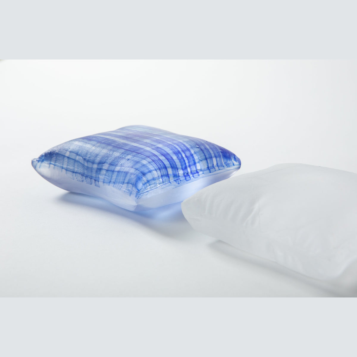 Close three-quarter view with the indigo pillow in front, the fine blue lattice visible within the glass.