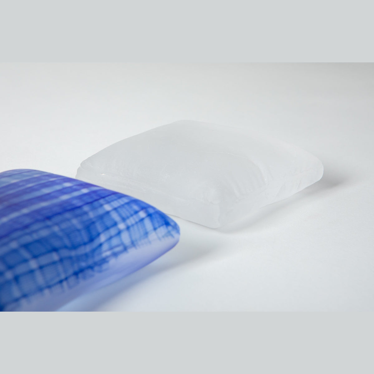 The white frosted pillow in front and the indigo behind, light passing through the translucent white glass.