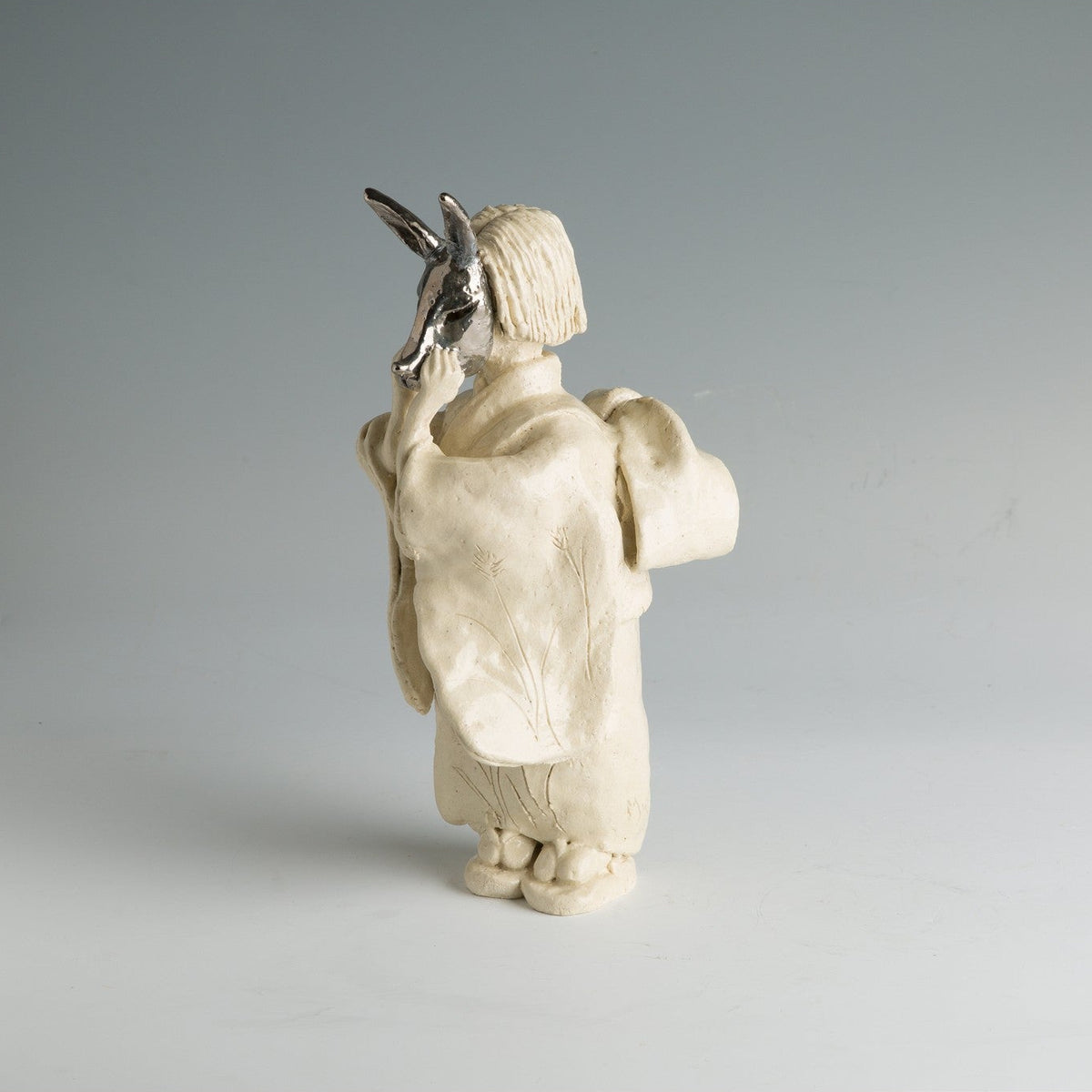 Vue de dos de la figure, montrant la tombée du kimono et l'arrière du masque de renard.