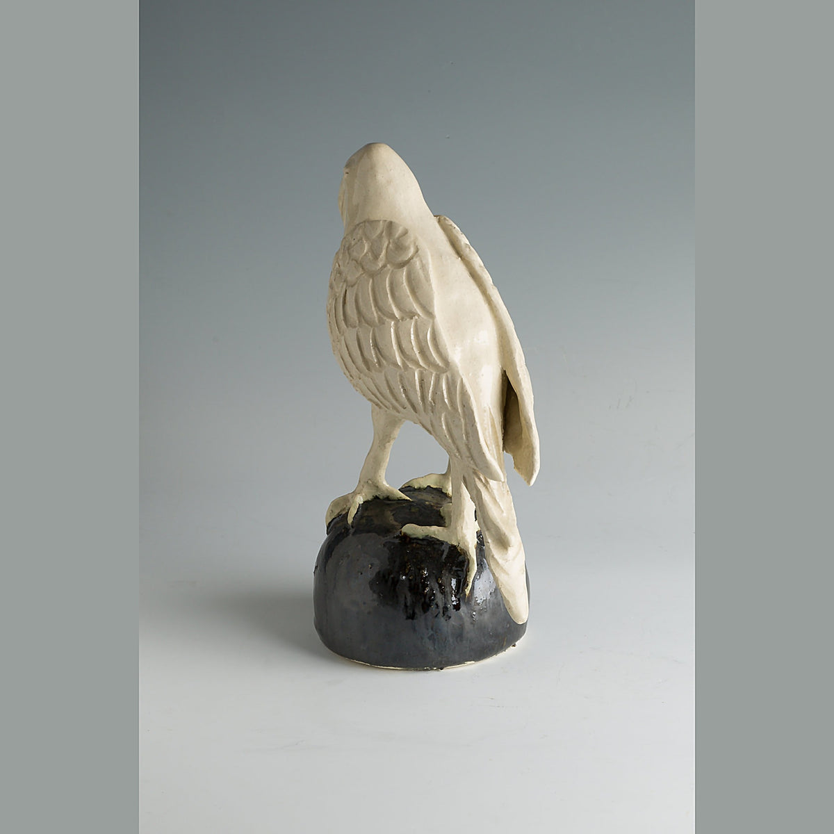 View of the crow from behind, the incised feathers fanning across the back and wings above the black base.