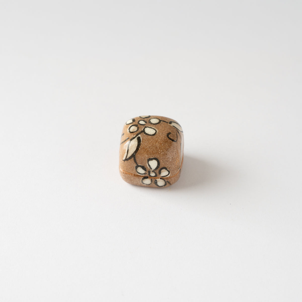 Turned top view of the Oribe miniature ceramic KOGO box, showing hand-painted plum blossom details in white slip and iron underglaze.