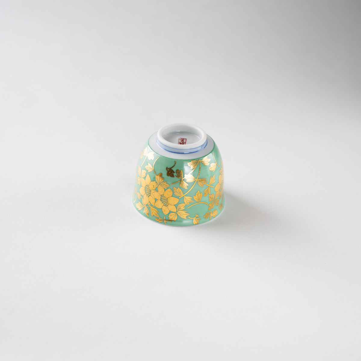 Inverted bottom view of the GUINOMI sake cup by Mitsuru Yoshida, displaying the circular foot ring, blue concentric lines, and red square artist seal.