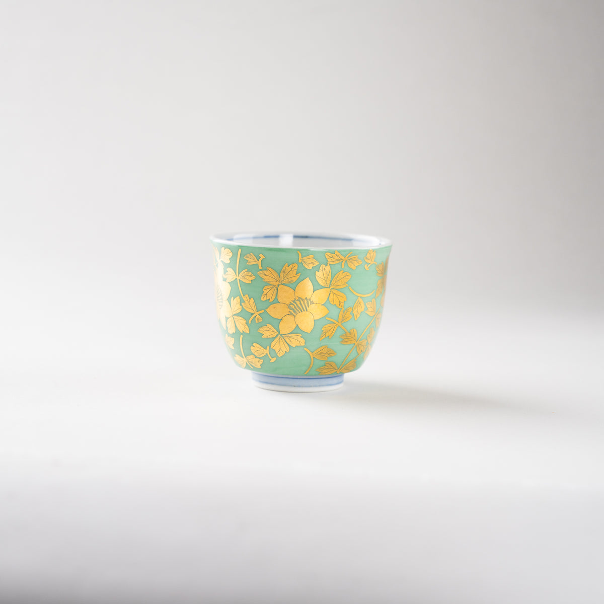 Turned perspective of the Kinrande ceramic GUINOMI by Mitsuru Yoshida, showing the graceful flow of gilded blossoms and the blue foot line.