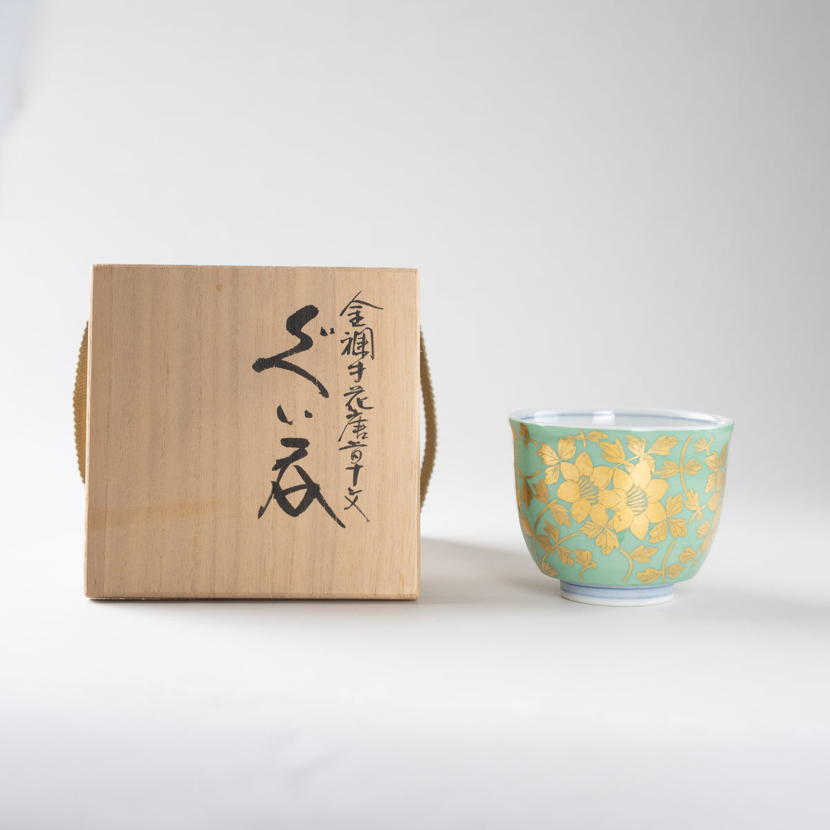 The Kinrande floral arabesque GUINOMI cup by Mitsuru Yoshida placed alongside its authentic inscribed wooden tomobako box.