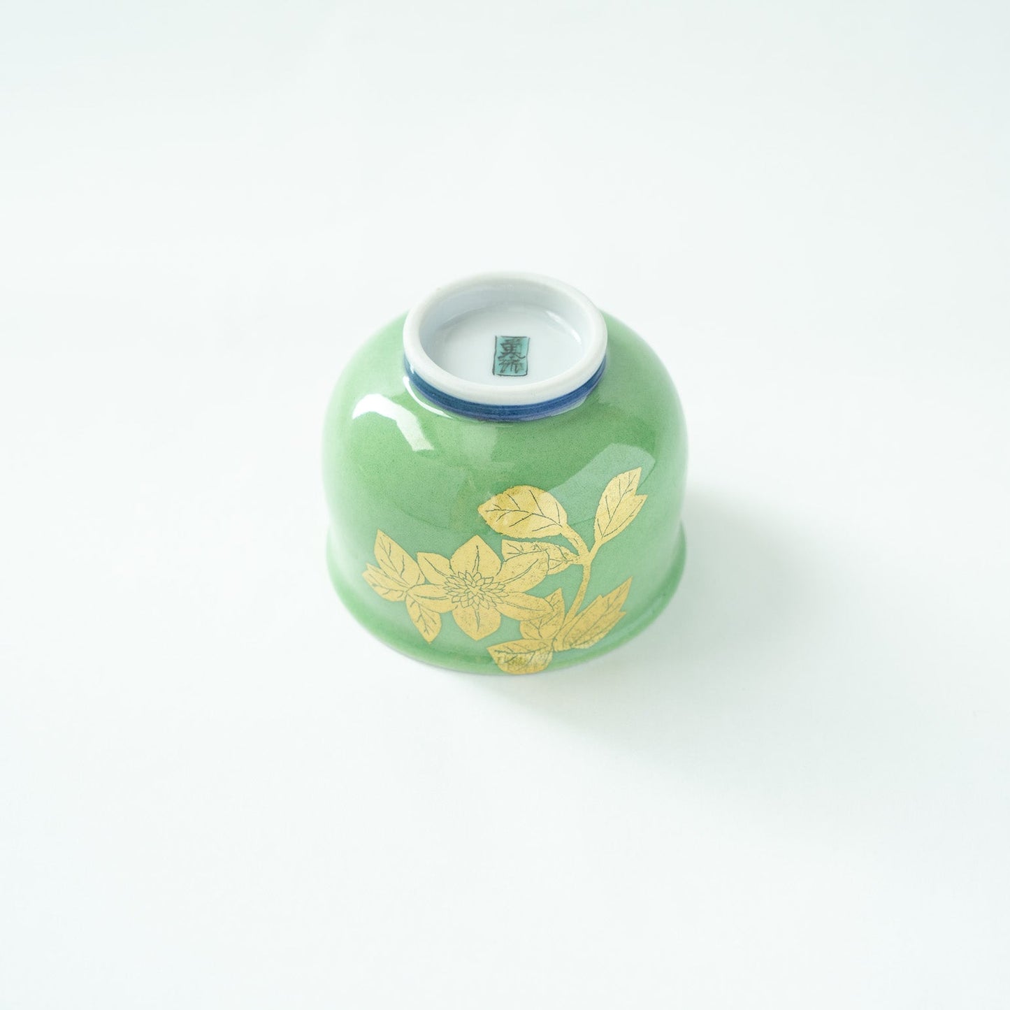 Inverted view of the GUINOMI, revealing the flawless white porcelain base with the artist's handwritten name signature in blue.