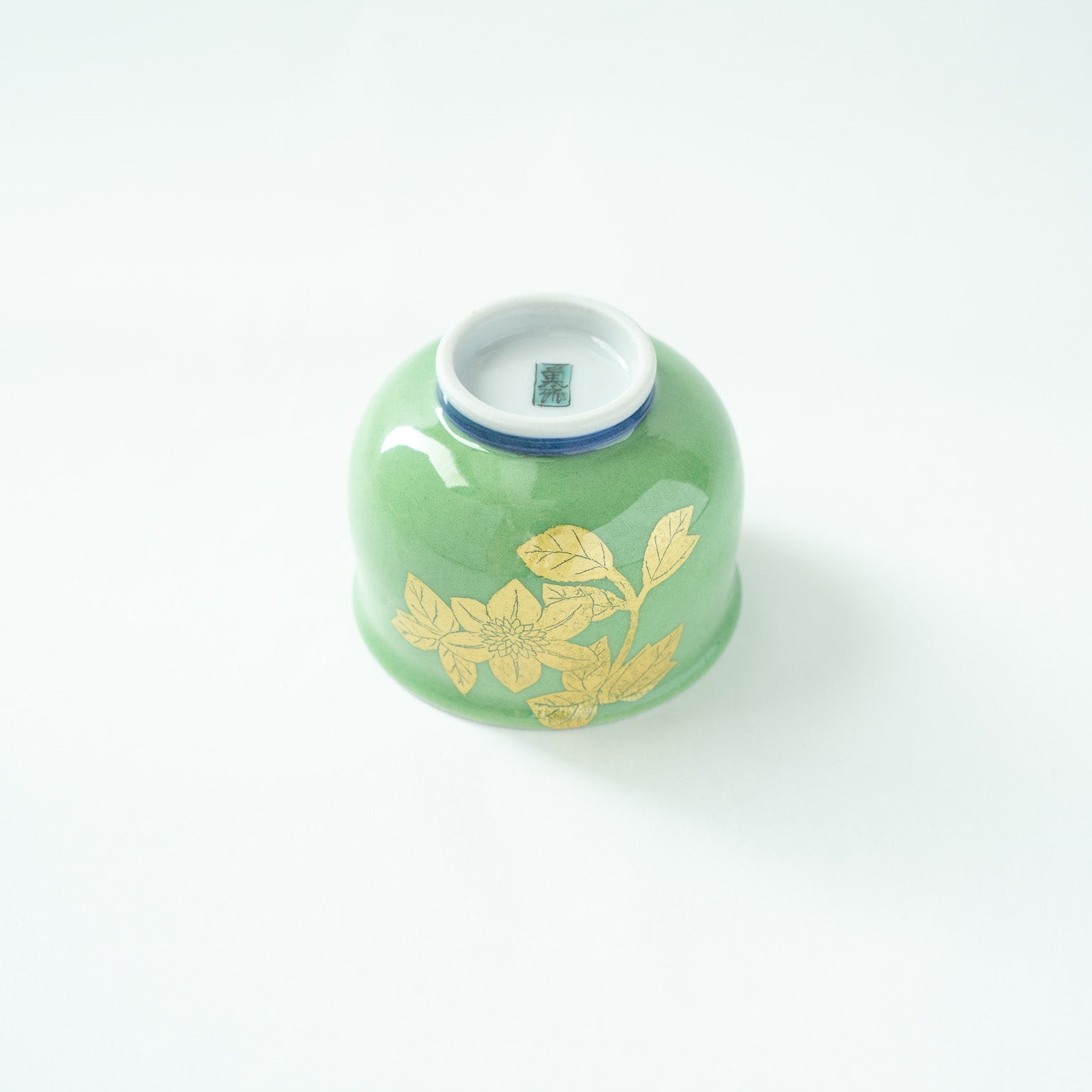 Inverted view of the GUINOMI, revealing the flawless white porcelain base with the artist's handwritten name signature in blue.