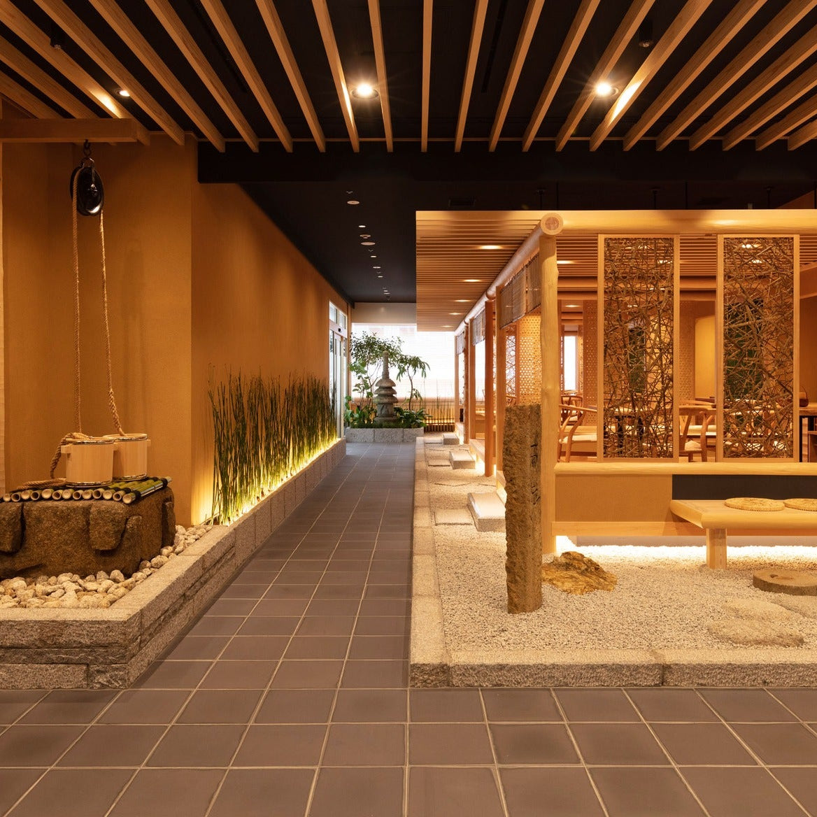 A stone-paved passage flanked by a well and a gravel garden with a stone marker, Japanese architecture filling a single high floor.