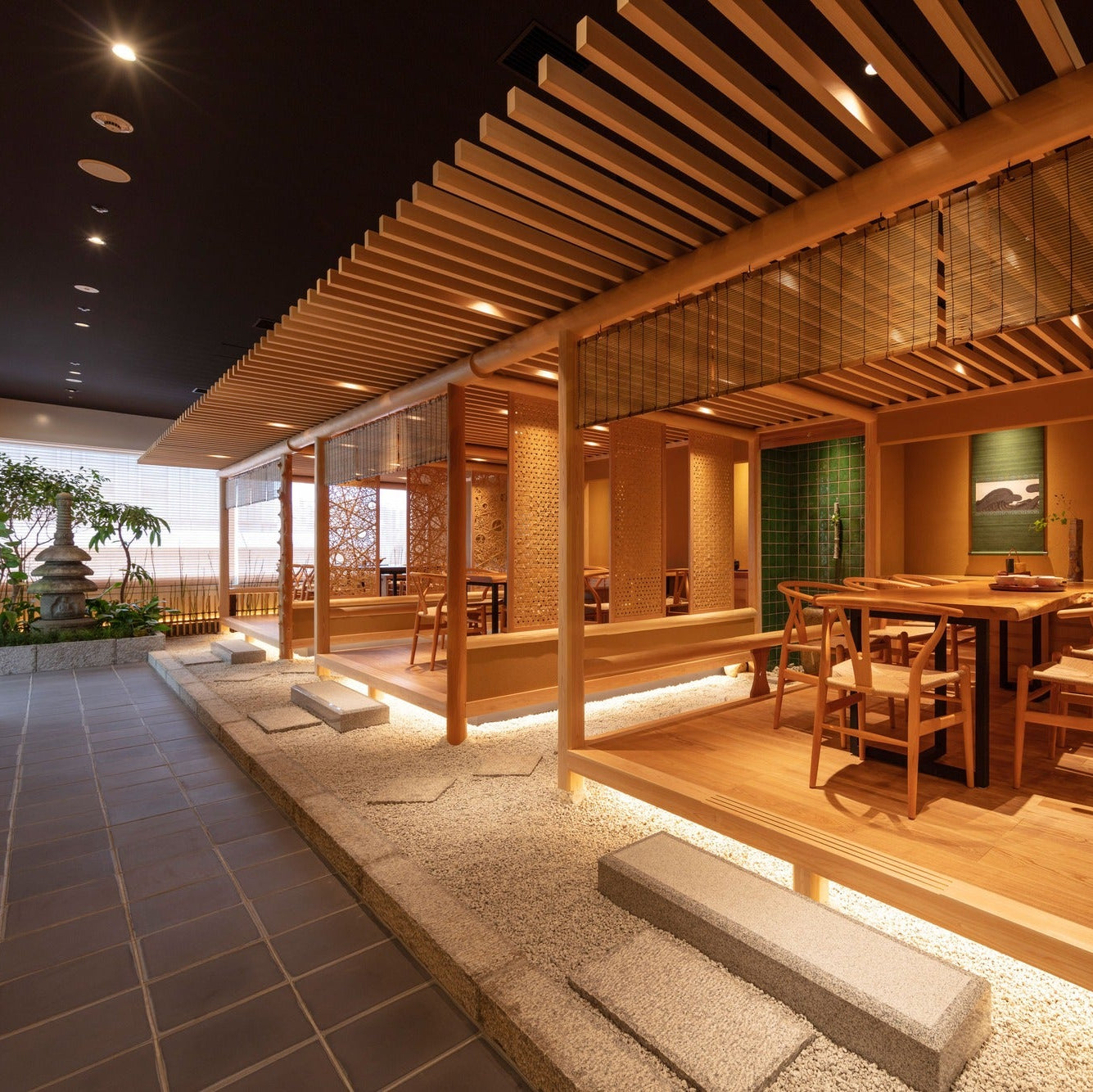 Looking from the corridor toward the rooms, a stone lantern and stepping stones cross a bed of white gravel.