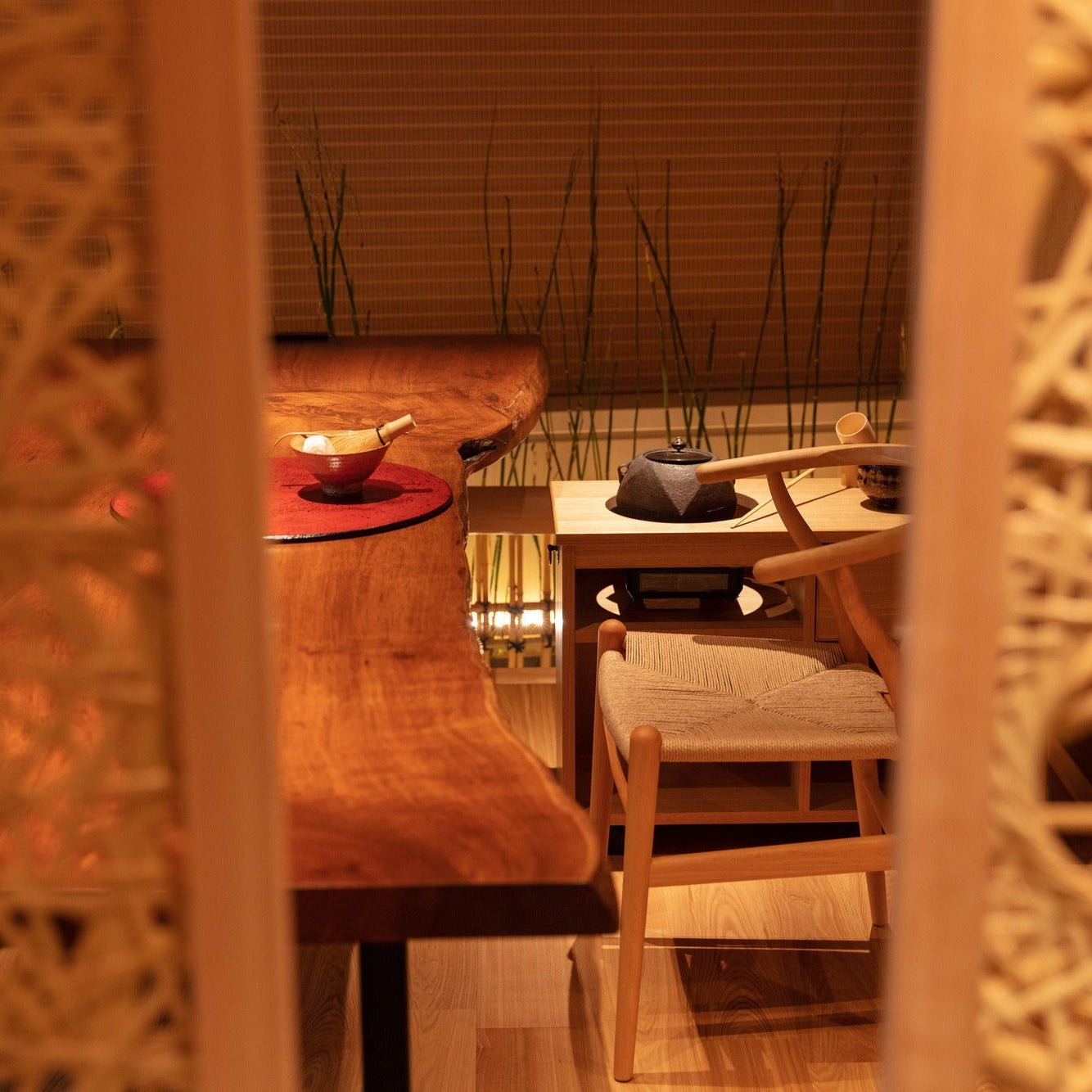 Glimpsed between lattice panels, an iron kettle and tea bowls wait on a counter, the tools of chashitsu.
