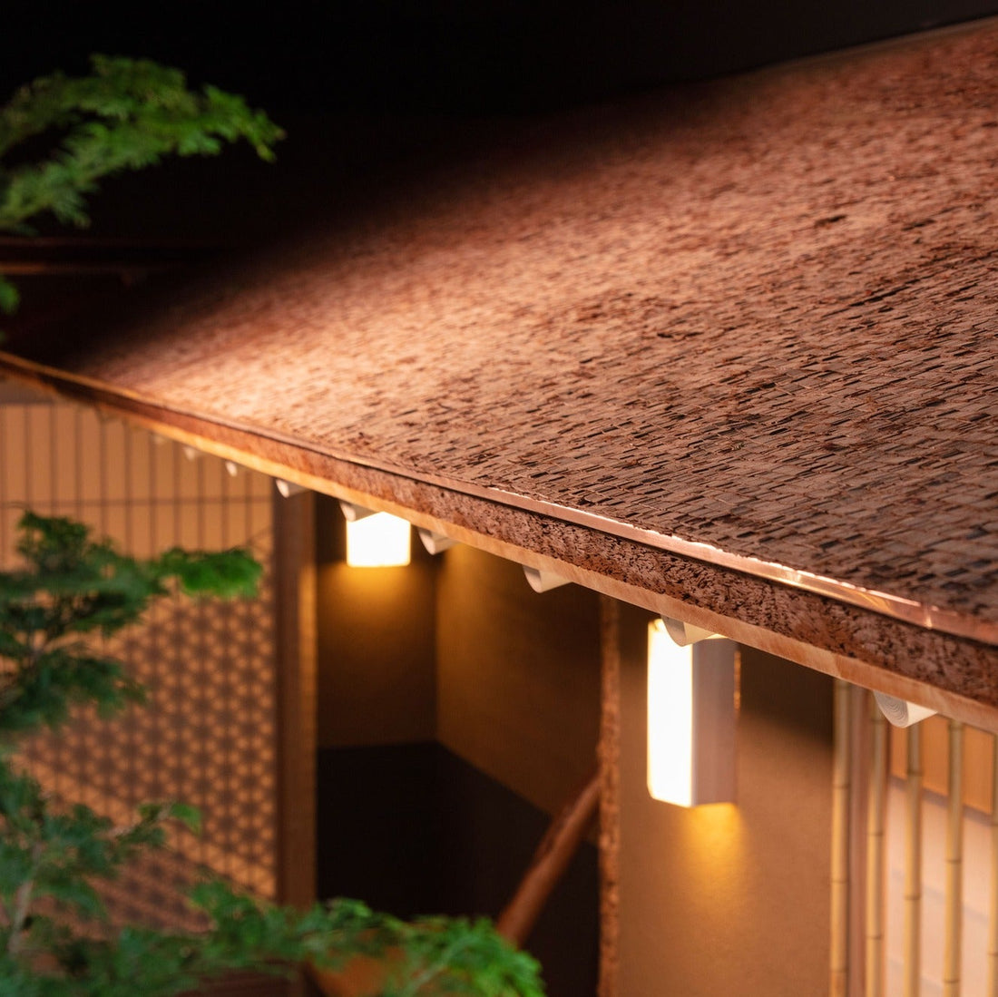 Close view of a hand-split timber shingle roof and its copper edge, built indoors as a feat of Japanese architecture.