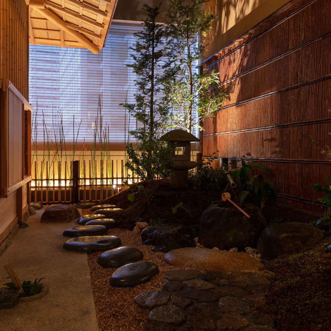 A roji garden of stepping stones, a stone lantern and a water basin, framed by reed walls, Japanese architecture brought indoors.