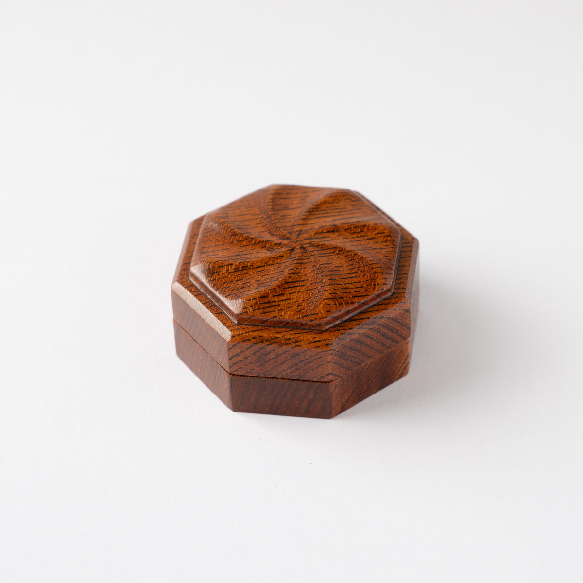 High-angle view of the closed octagonal Keyaki wood KOGO incense container by Osamu Oyama, focusing on the radiating carved spiral motif on the lid.