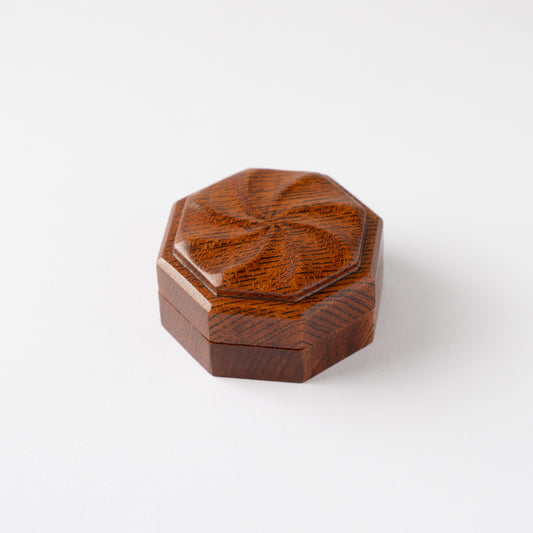 High-angle view of the closed octagonal Keyaki wood KOGO incense container by Osamu Oyama, focusing on the radiating carved spiral motif on the lid.