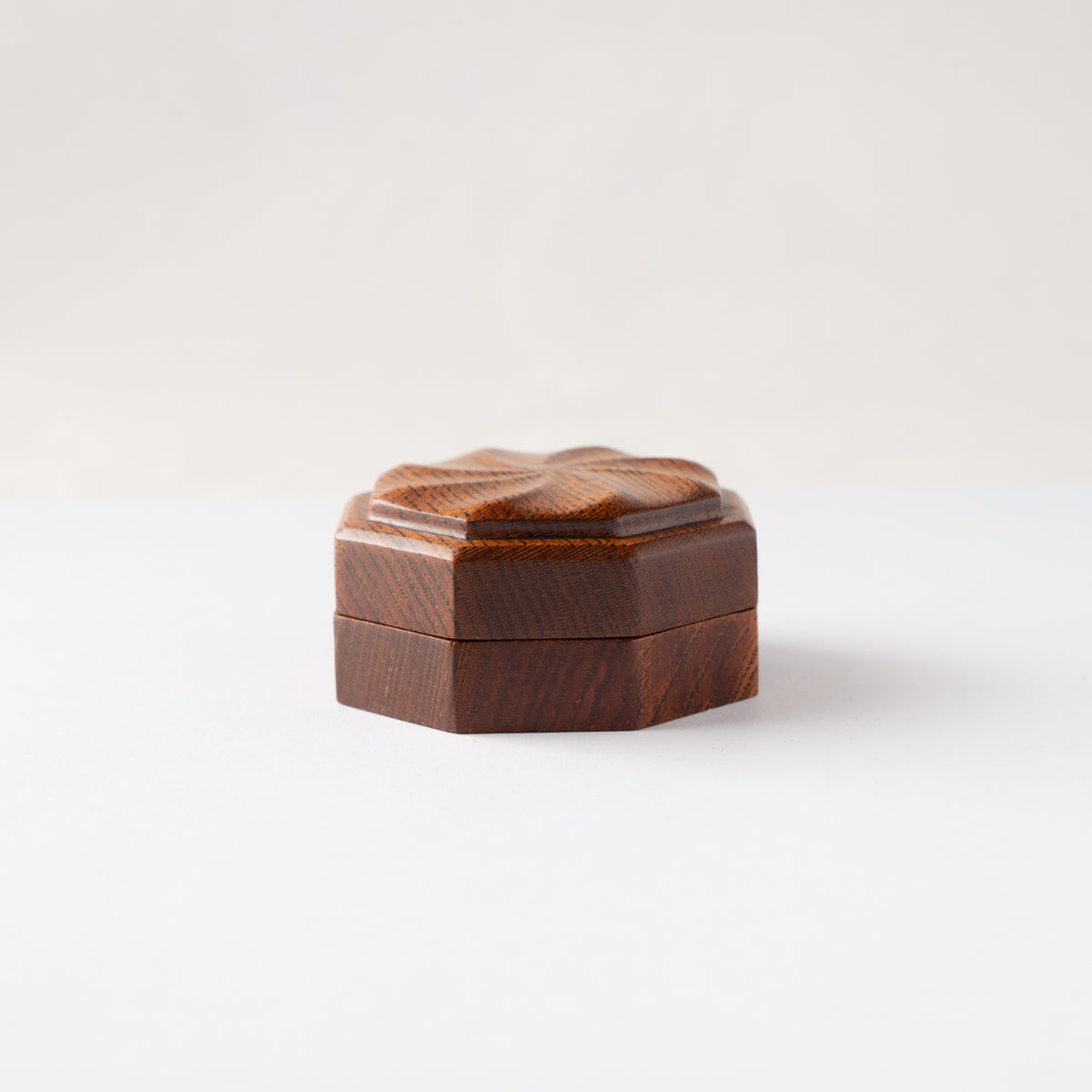 Straight eye-level studio view of the closed octagonal Keyaki wood KOGO incense container showing the fine wood grain alignment.