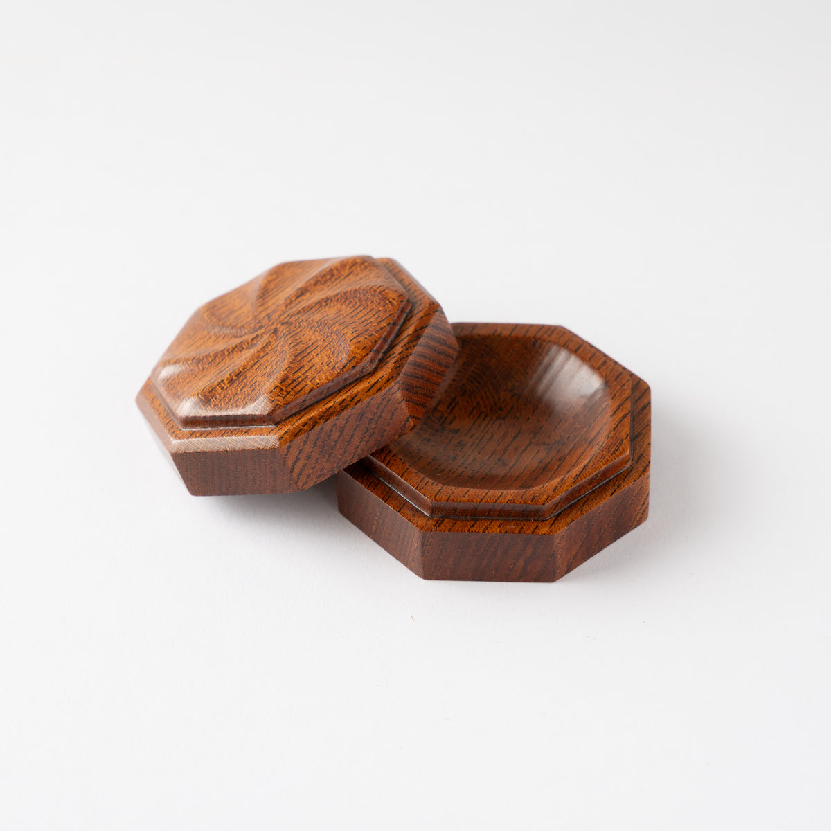 Turned side view of the octagonal Keyaki wood KOGO incense container with lid resting open beside the base, showing the precise lip structure.