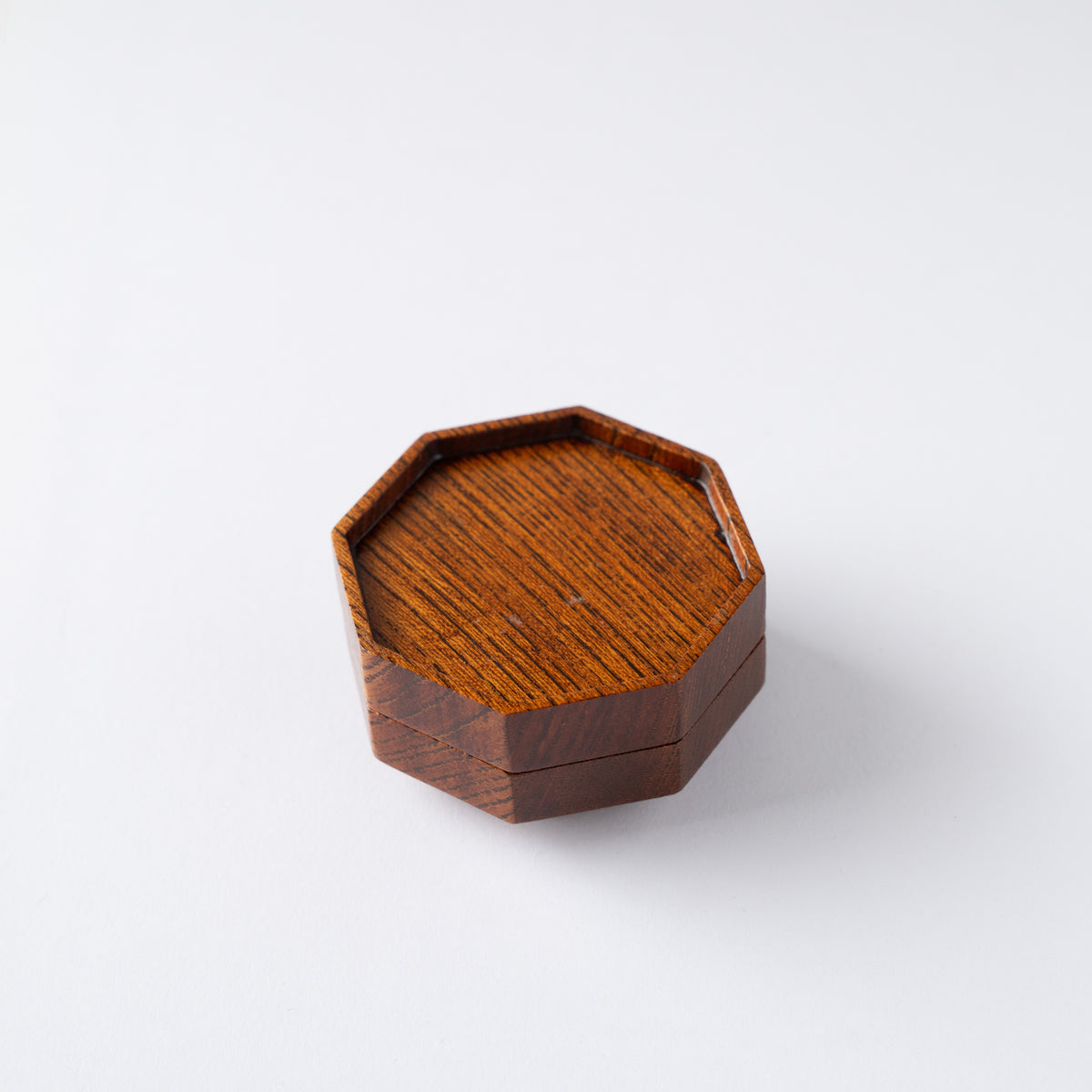 High-angle turned view of Osamu Oyama's octagonal Keyaki wood KOGO incense container, showing rich natural wood grain and precise lacquered edges.