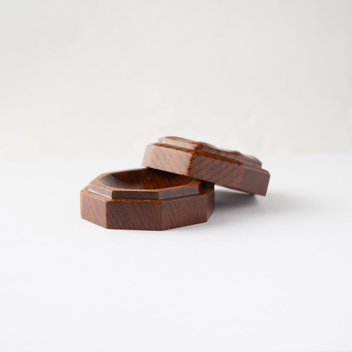 Low-angle profile view of the open octagonal Keyaki wood KOGO incense container by Osamu Oyama showing the seamless joint fit.