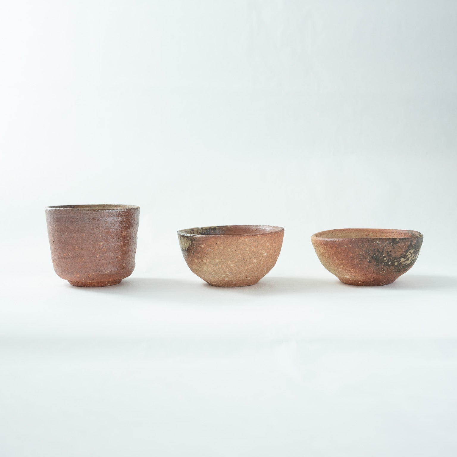 Another side view of the three unglazed Shigaraki cups, emphasizing the organic silhouettes and hand-formed contours of each vessel.
