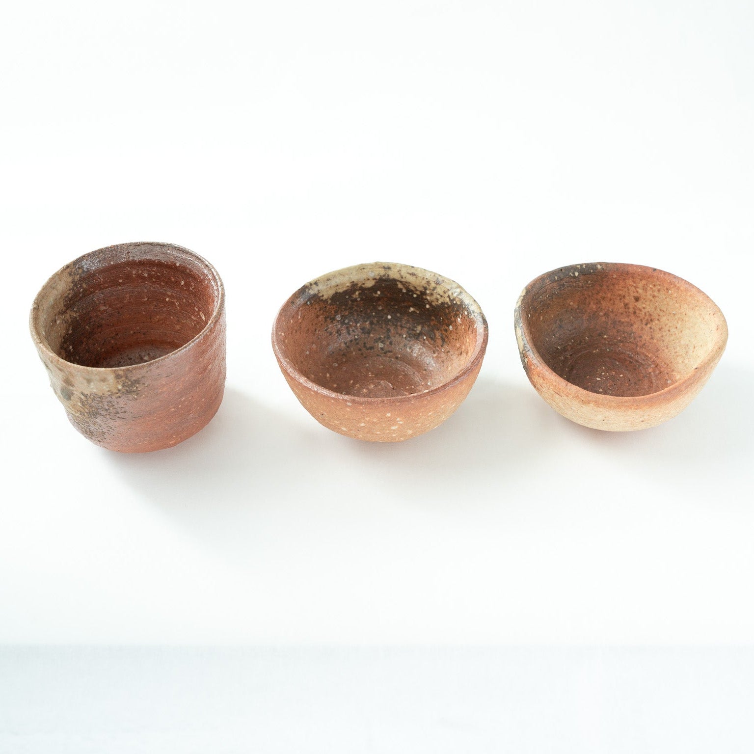 Close-up top view looking inside the vessels, displaying the rough feldspar grains and deep earthy textures lining the inner walls.
