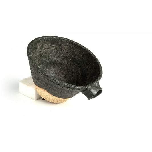 View from above and to the side showing the black interior, the short pulled spout and the pale bare base.