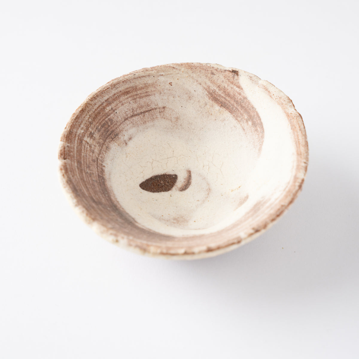 Top-down perspective looking into the shallow white basin of Ryusuke Asai's GUINOMI cup with dynamic iron wash decoration.