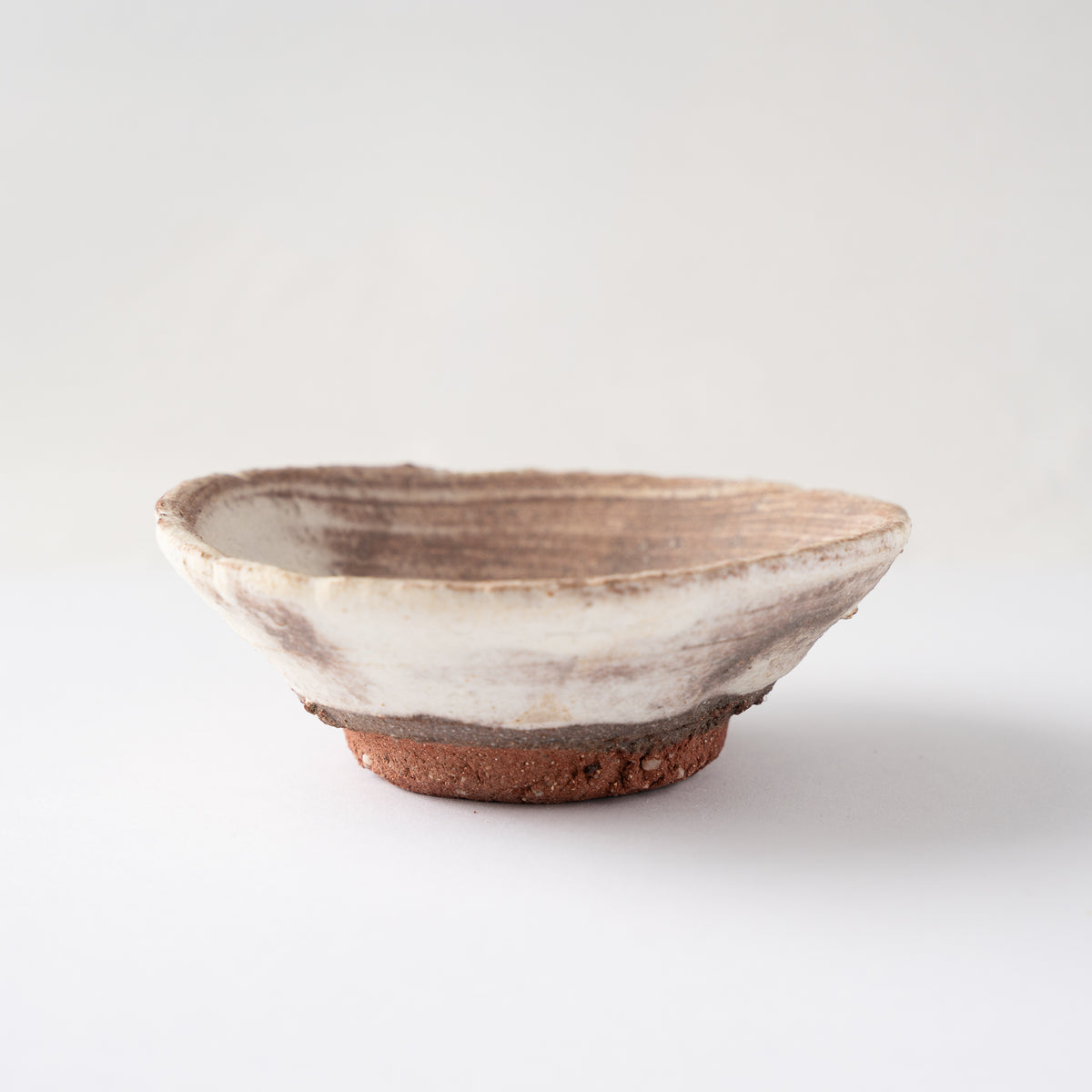 Low-angle profile of Ryusuke Asai's shallow ceramic GUINOMI, displaying its wide saucer-like rim and red foot ring.