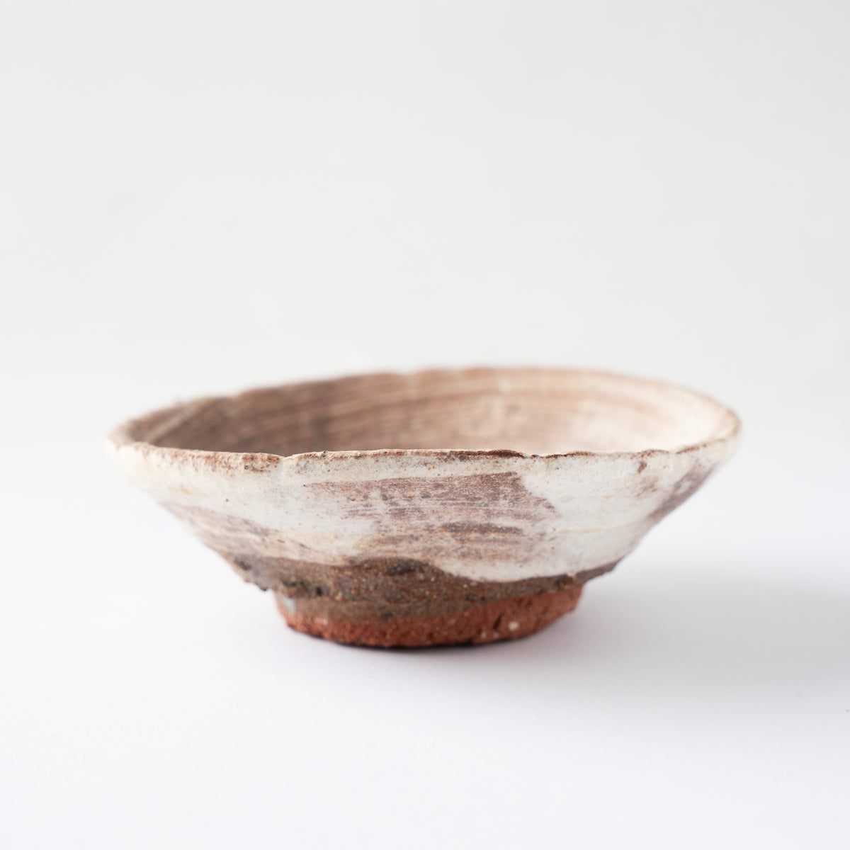 Underside view of the shallow GUINOMI by Ryusuke Asai, highlighting the contrast between white slip glaze and rustic unglazed clay.