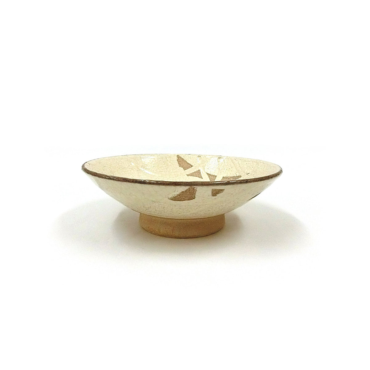 Side view of a single bowl showing the wide low cone form, small foot and iron-brown rim.