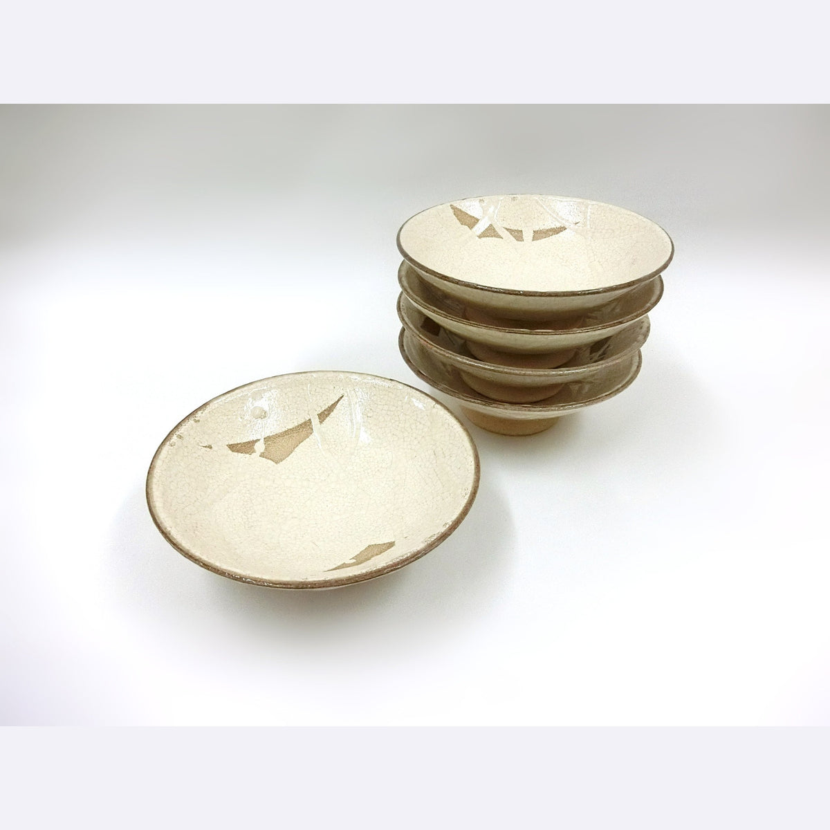 The bowls stacked with one set apart, photographed in soft light on a pale surface.