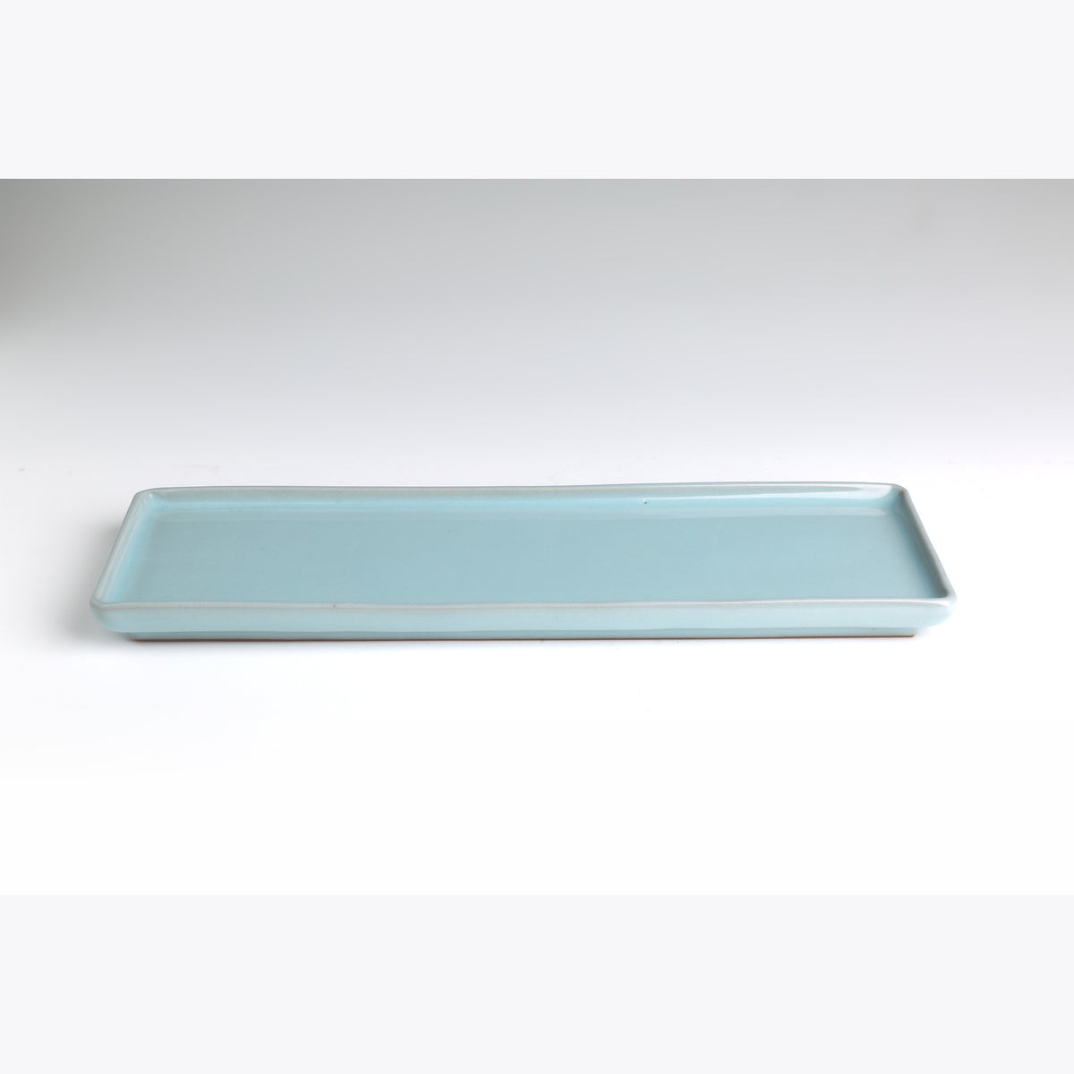 The celadon plate on a white ground, showing the low straight lip and even glaze.