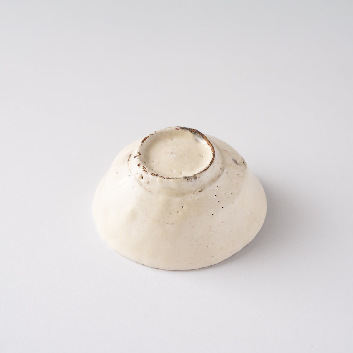 Inverted view of Seiya Toyoba's Kohiki SAKAZUKI sake cup, revealing the neat circular foot base and unglazed clay rim.