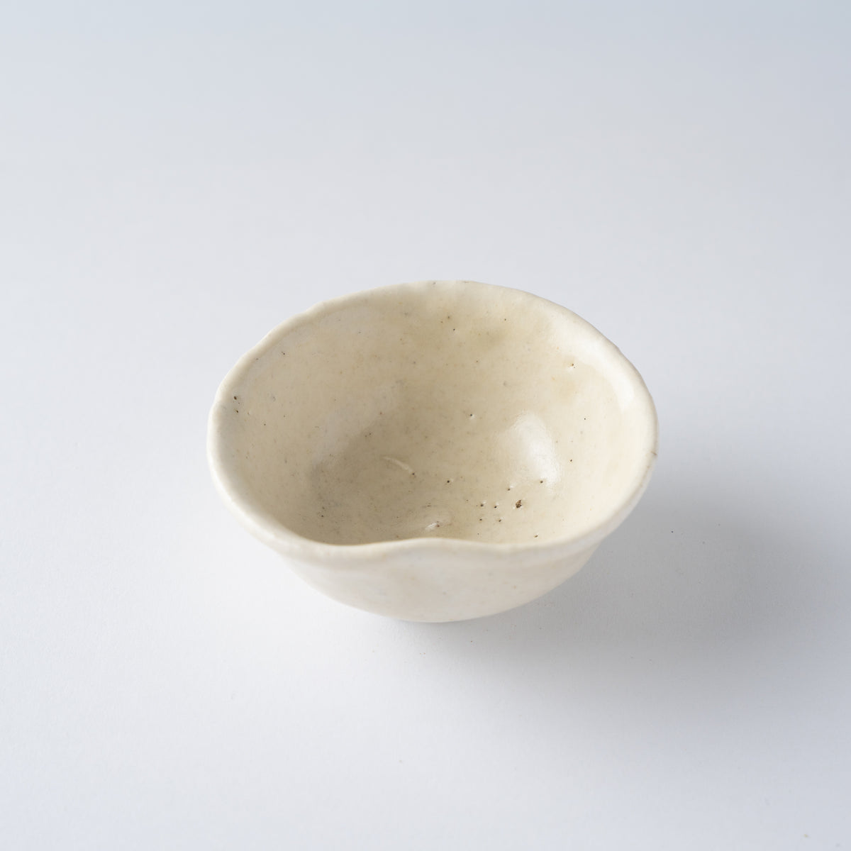 High-angle view looking into the wide creamy white basin of Seiya Toyoba's Kohiki SAKAZUKI sake cup.