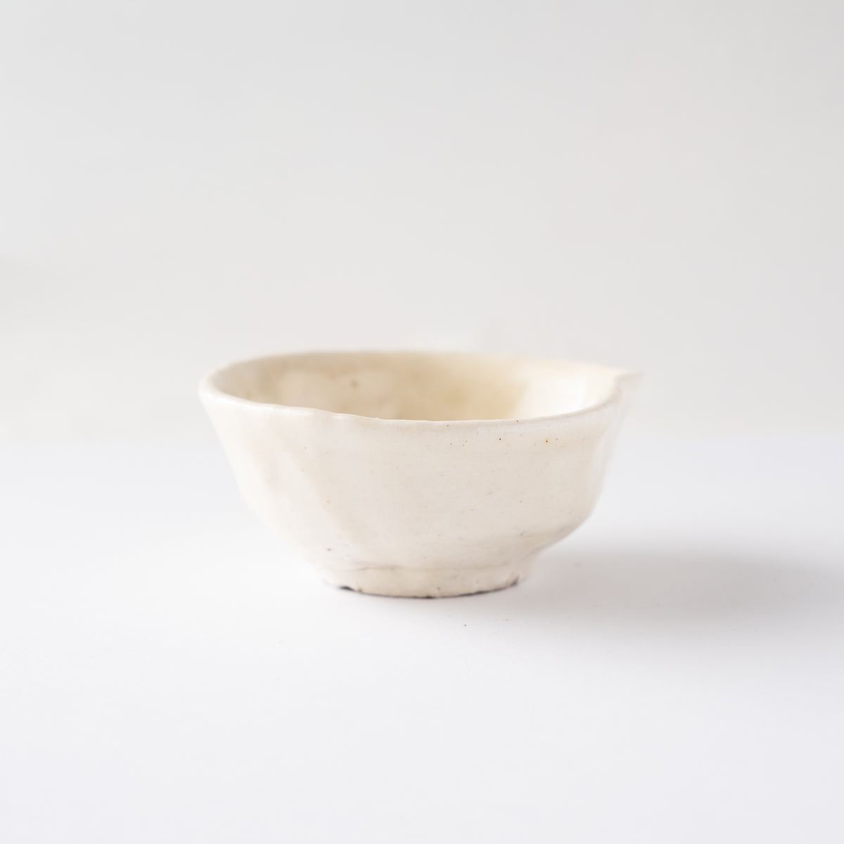 Side profile focusing on the subtle pinched lip detail on the rim of Seiya Toyoba's Kohiki SAKAZUKI cup.