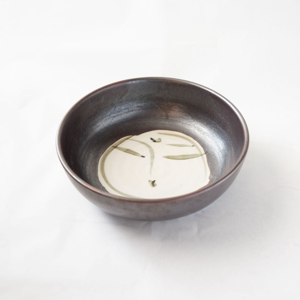 Interior view of the Shigaraki confectionery bowl, displaying the dark iron-glazed rim contrasted with a central white circular slip decorated with a poetic line drawing.