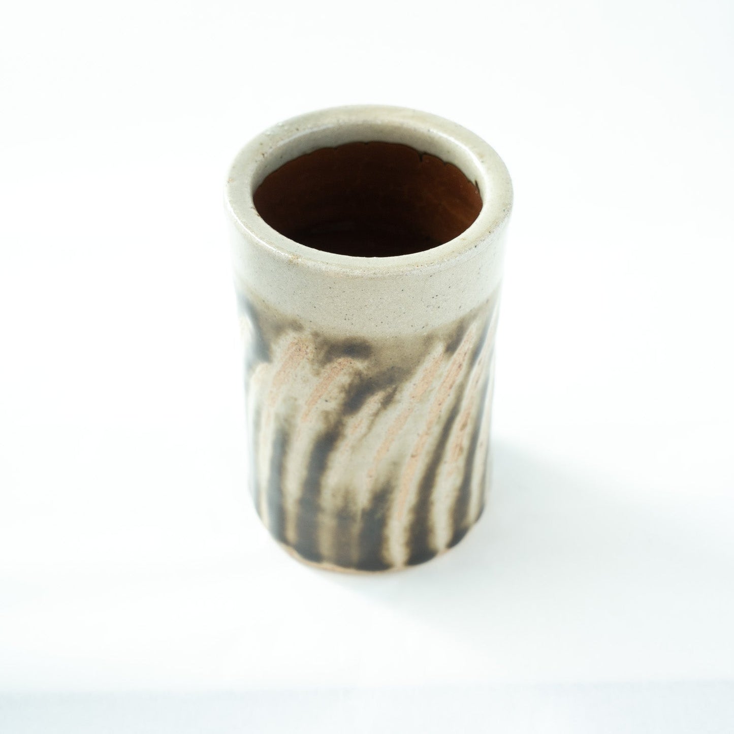 Top-down angled view looking into the hollow interior of the cylindrical vase, showing the thick rim and warm reddish-brown inside.