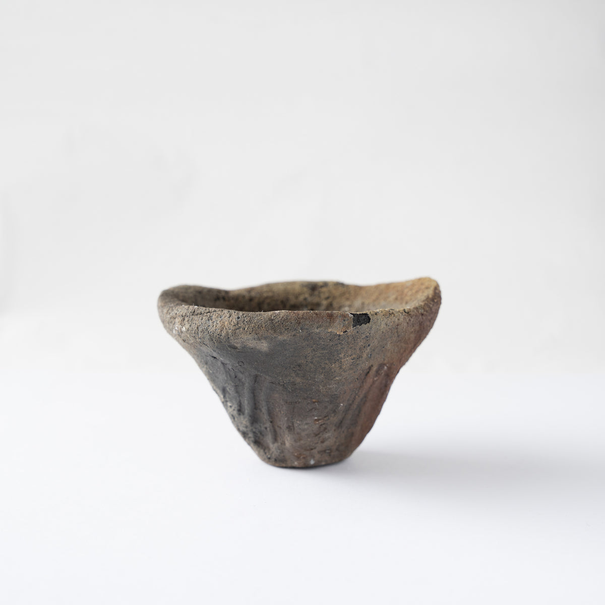Side view of Tamotsu Funakoshi’s ceramic GUINOMI, highlighting dark charcoal kiln scorch marks near the thick organic rim.