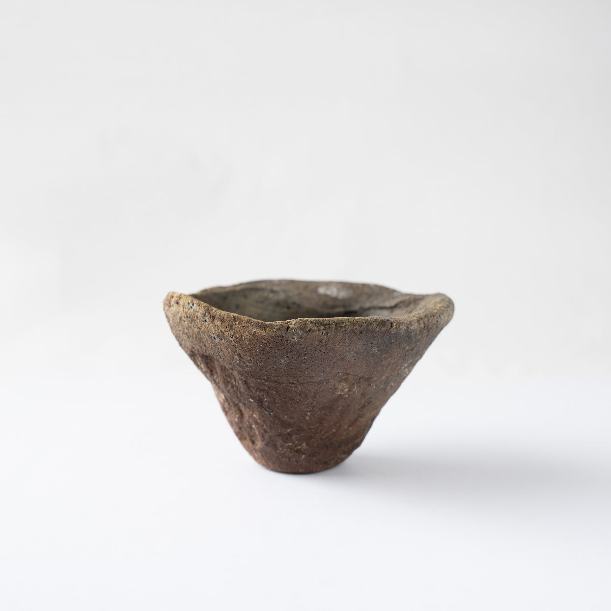 Front view of Tamotsu Funakoshi's ceramic GUINOMI sake cup, showing its flared conical form and rustic brown clay texture.
